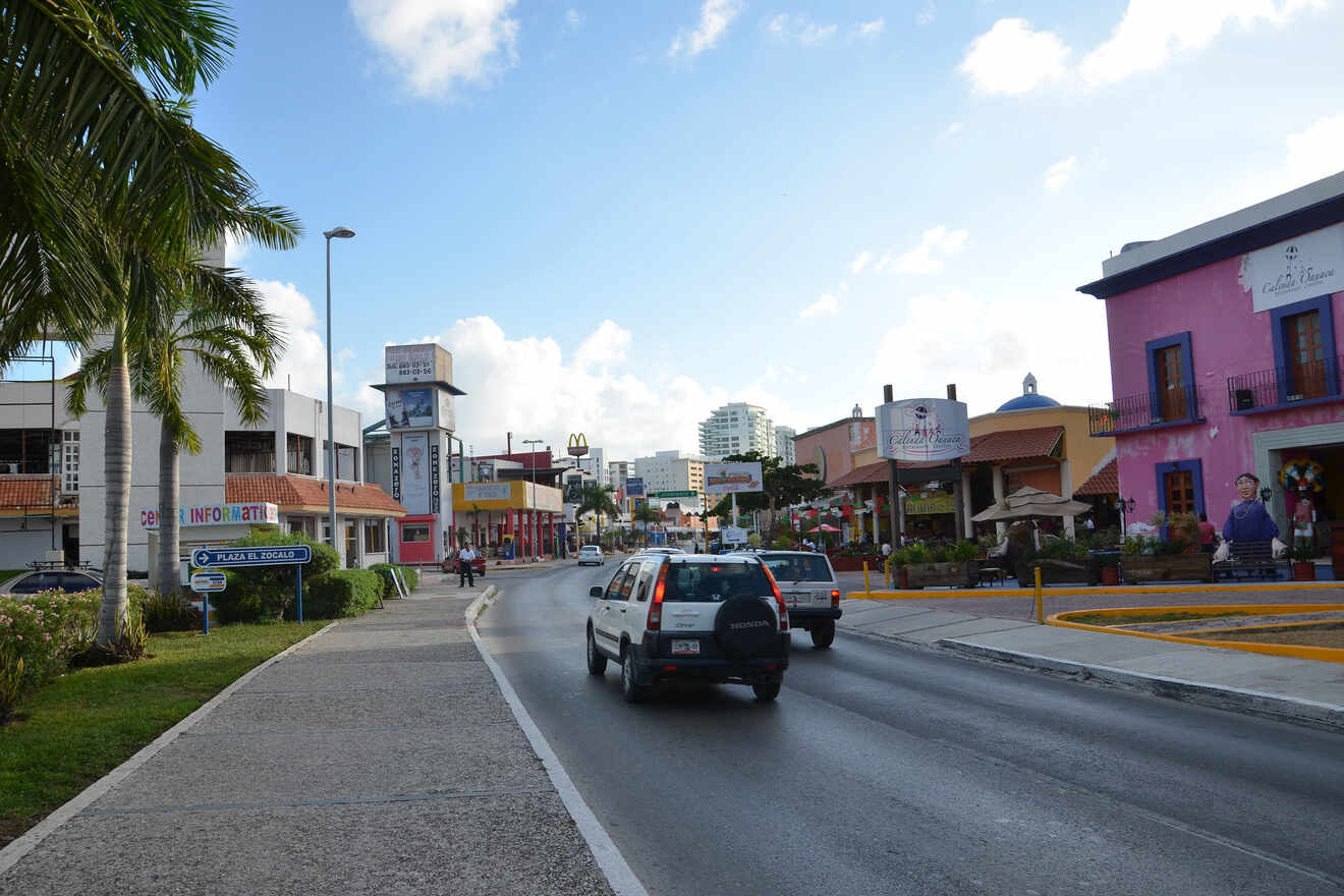 A street in cancun city with palm trees and buildings.