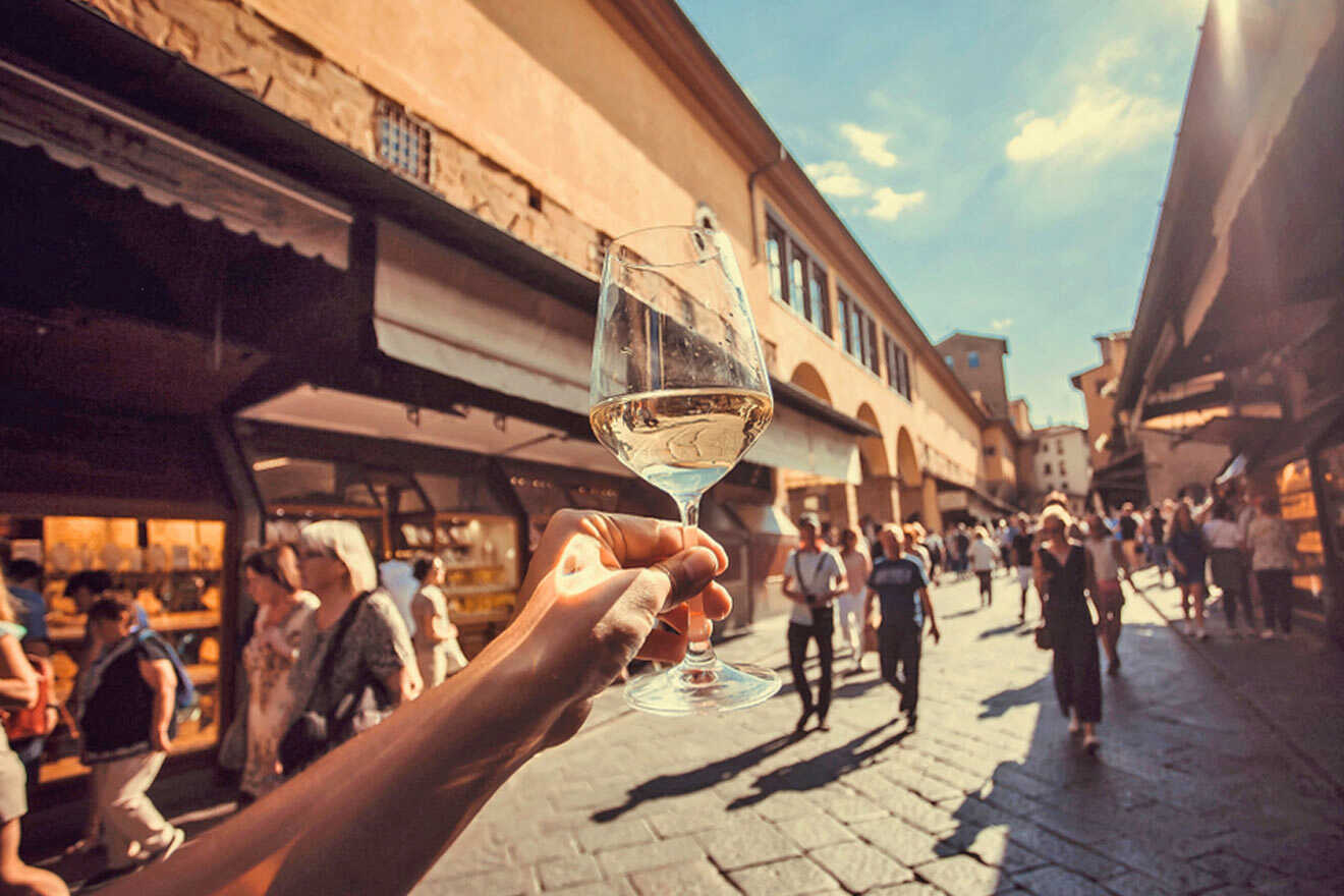 A person holding up a glass of wine on a street.