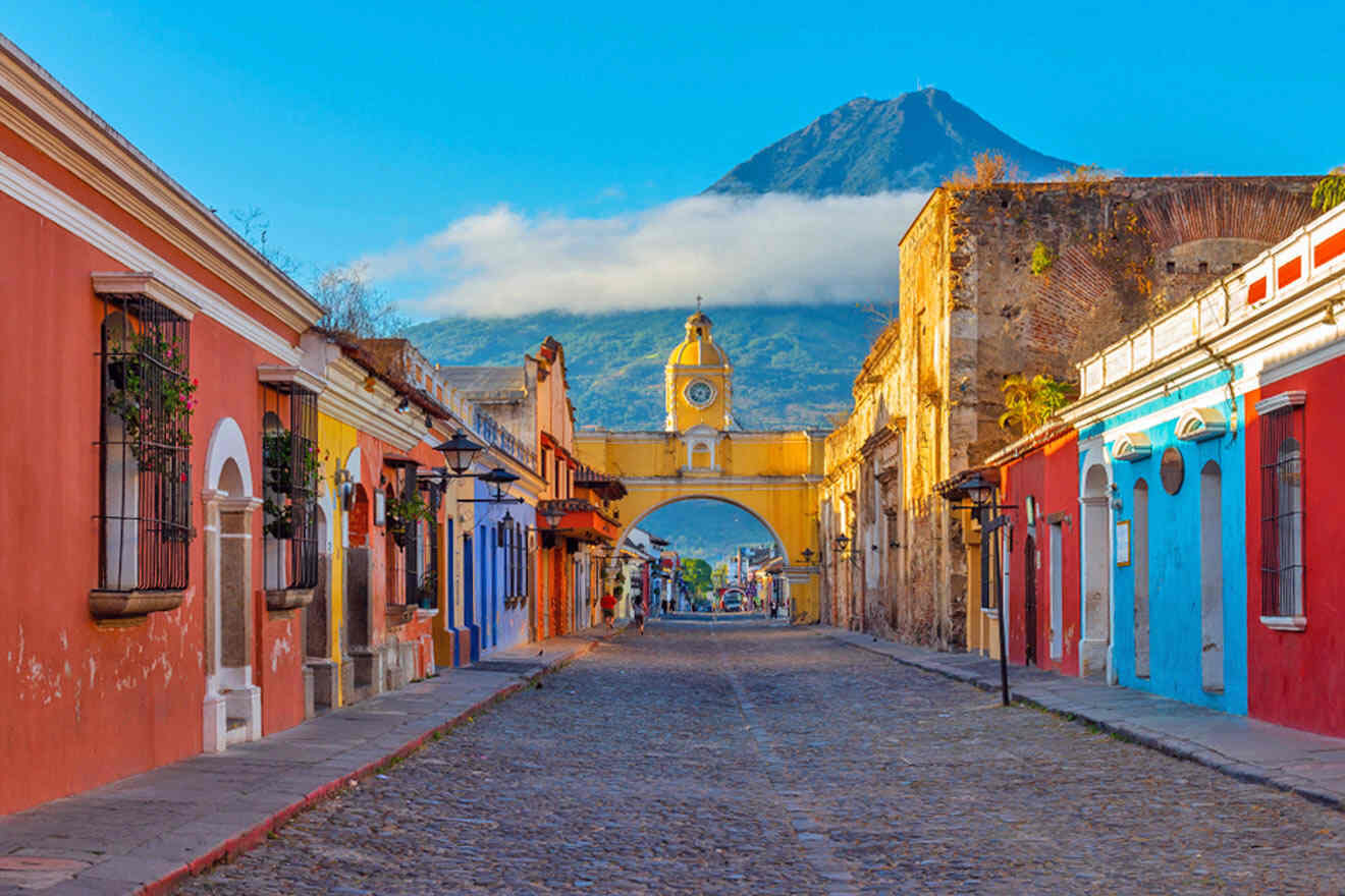 A cobblestone street with colorful buildings and a mountain in the background.