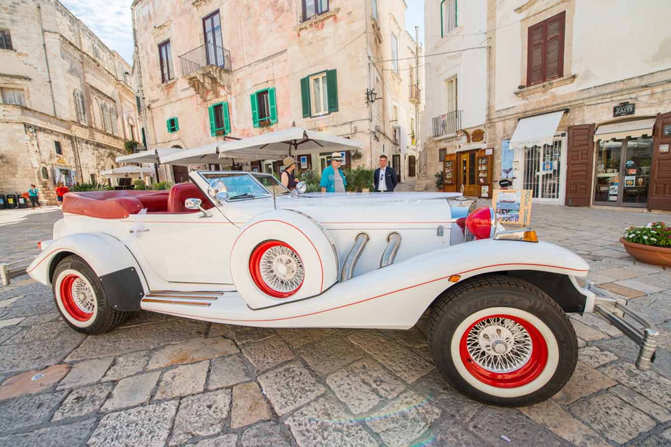 A white vintage car parked in a cobblestone street.