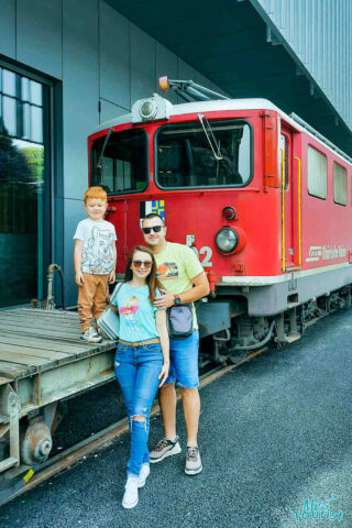 A family is posing in front of a red train.