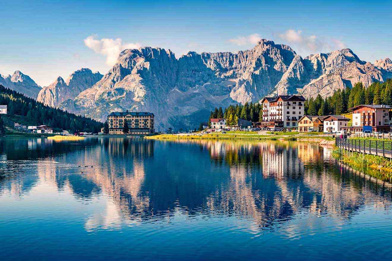 A lake surrounded by mountains and buildings in the dolomites.