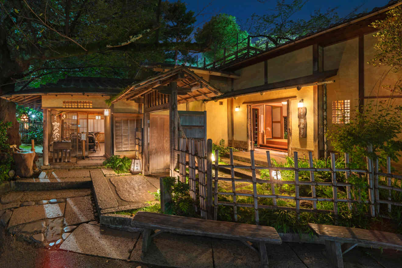 Traditional Japanese tea house at dusk with illuminated entrance and tranquil garden seating.