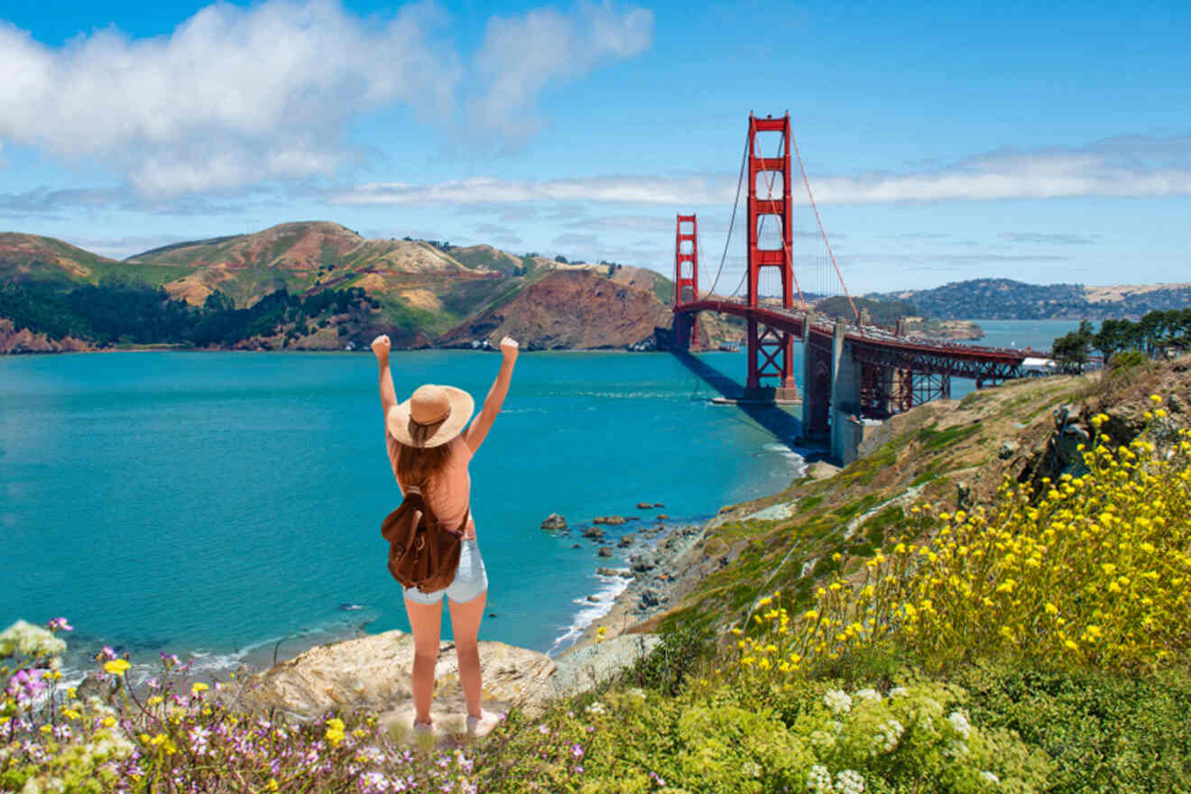 A woman is standing on top of a hill overlooking the golden gate bridge.