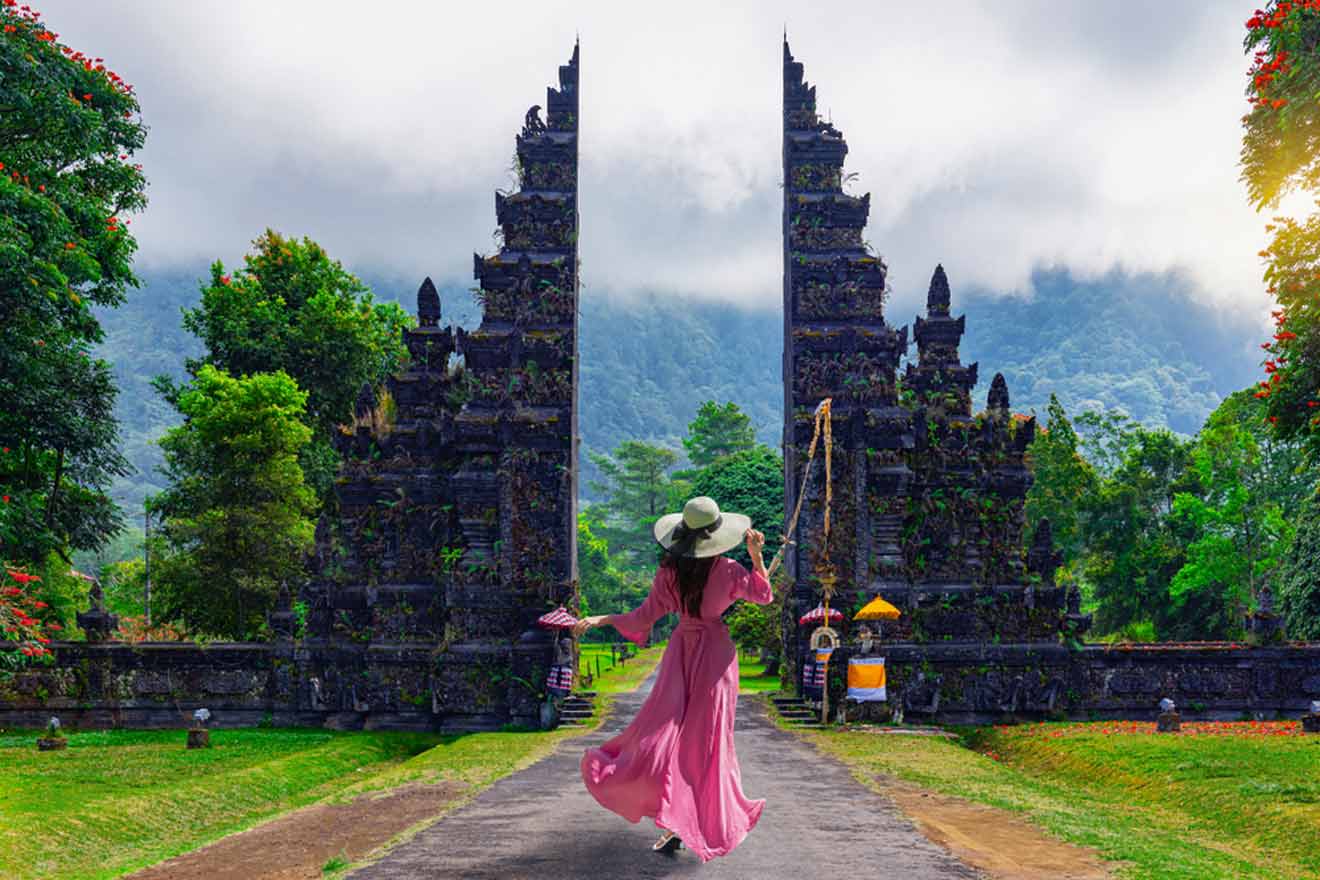A woman in a pink dress walking down a path near famouse Bali gate
