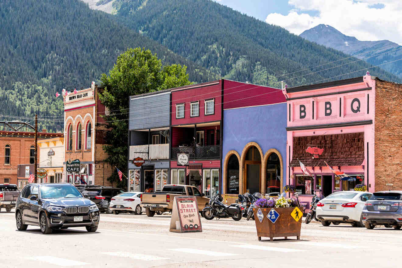 A small town in colorado with mountains in the background and parked cars