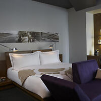 A hotel room with a bed and a purple couch.