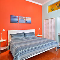 A bed in a bedroom with orange walls.