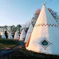 A row of white teepees in a field.