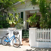 A blue bicycle is parked in front of a white picket fence.