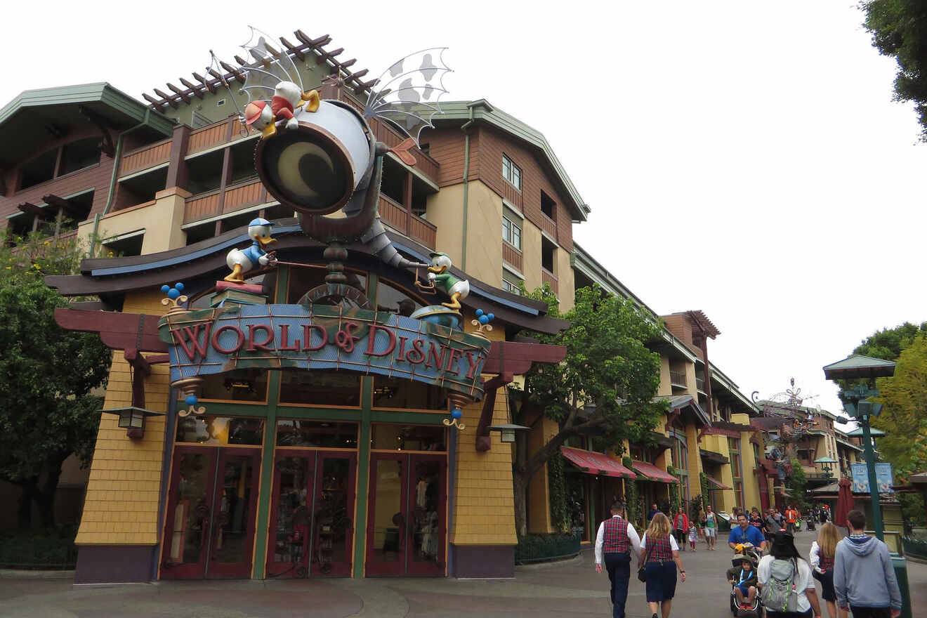 people walking on a street next to a building with a sign saying world of disney