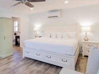A white bedroom with hardwood floors and a ceiling fan.