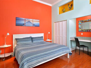 A bedroom with orange walls and a bed.