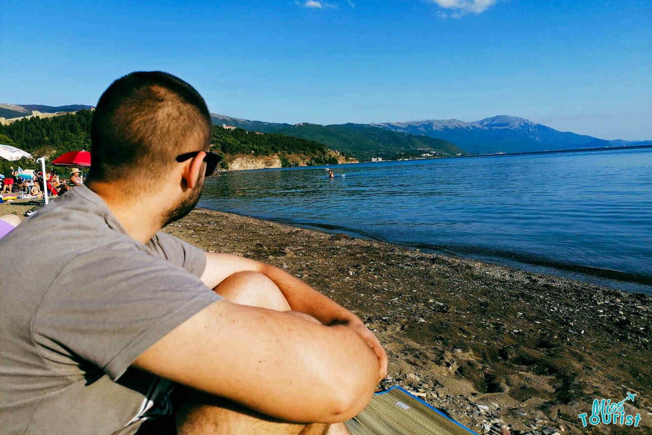 a guy sitting on a beach by lake Daljan