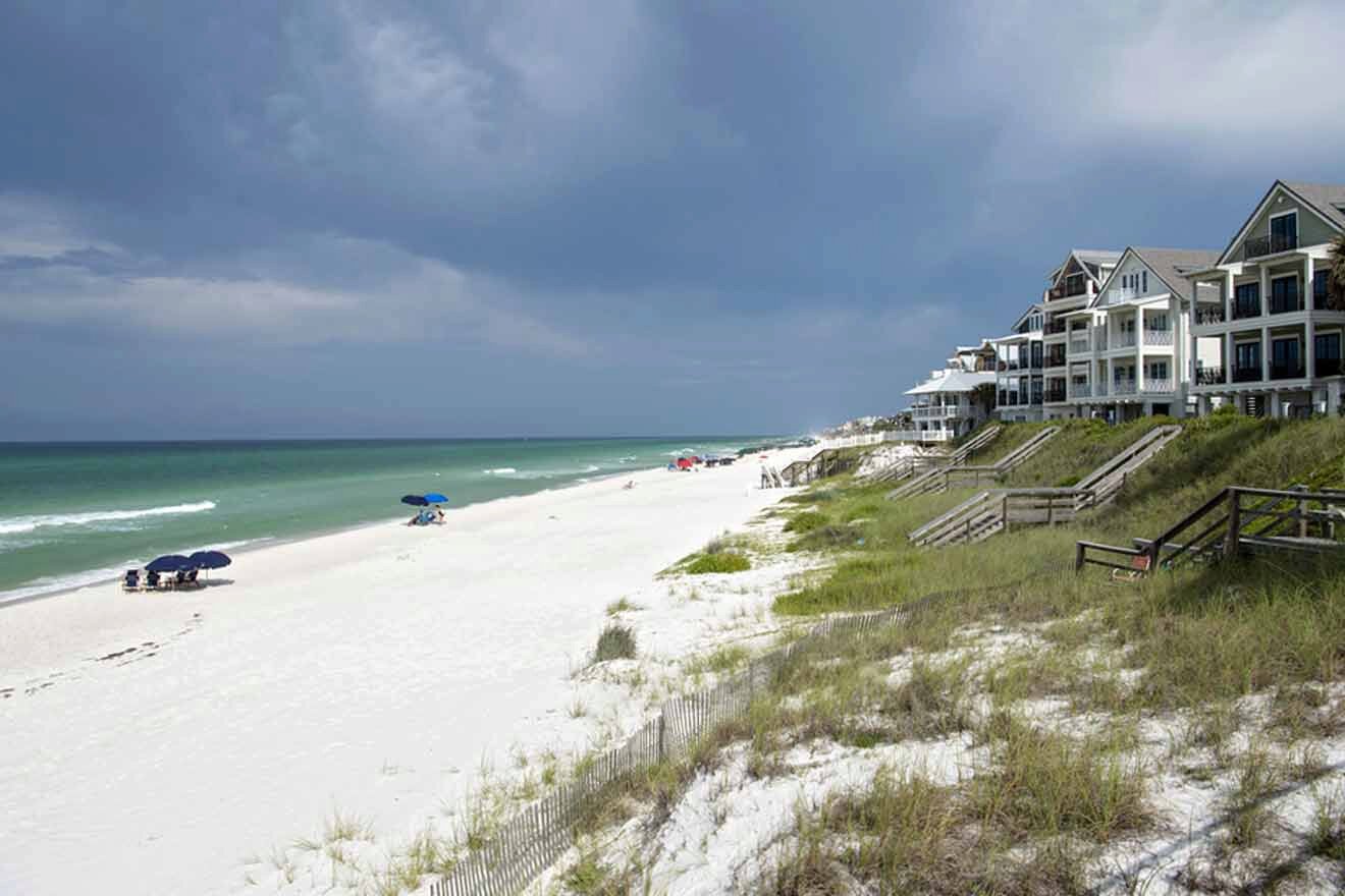 The beach is lined with white houses and umbrellas.