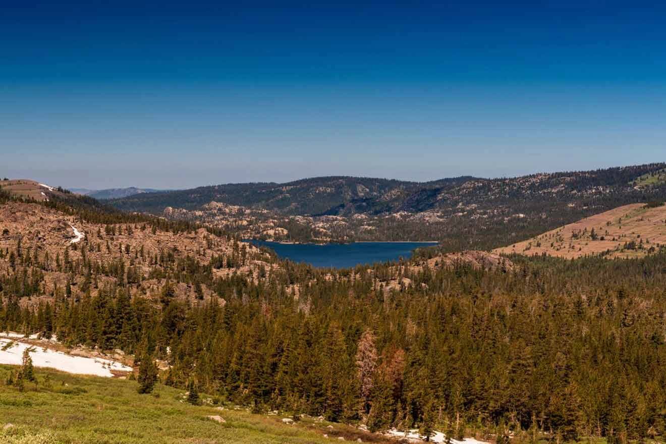 view from a trail of a lake surrounded by hills and trees