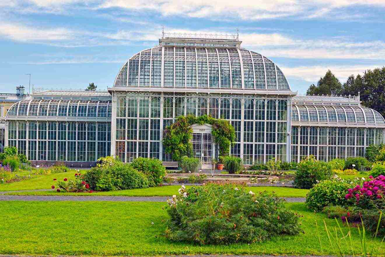 A large glass house in the middle of a garden.
