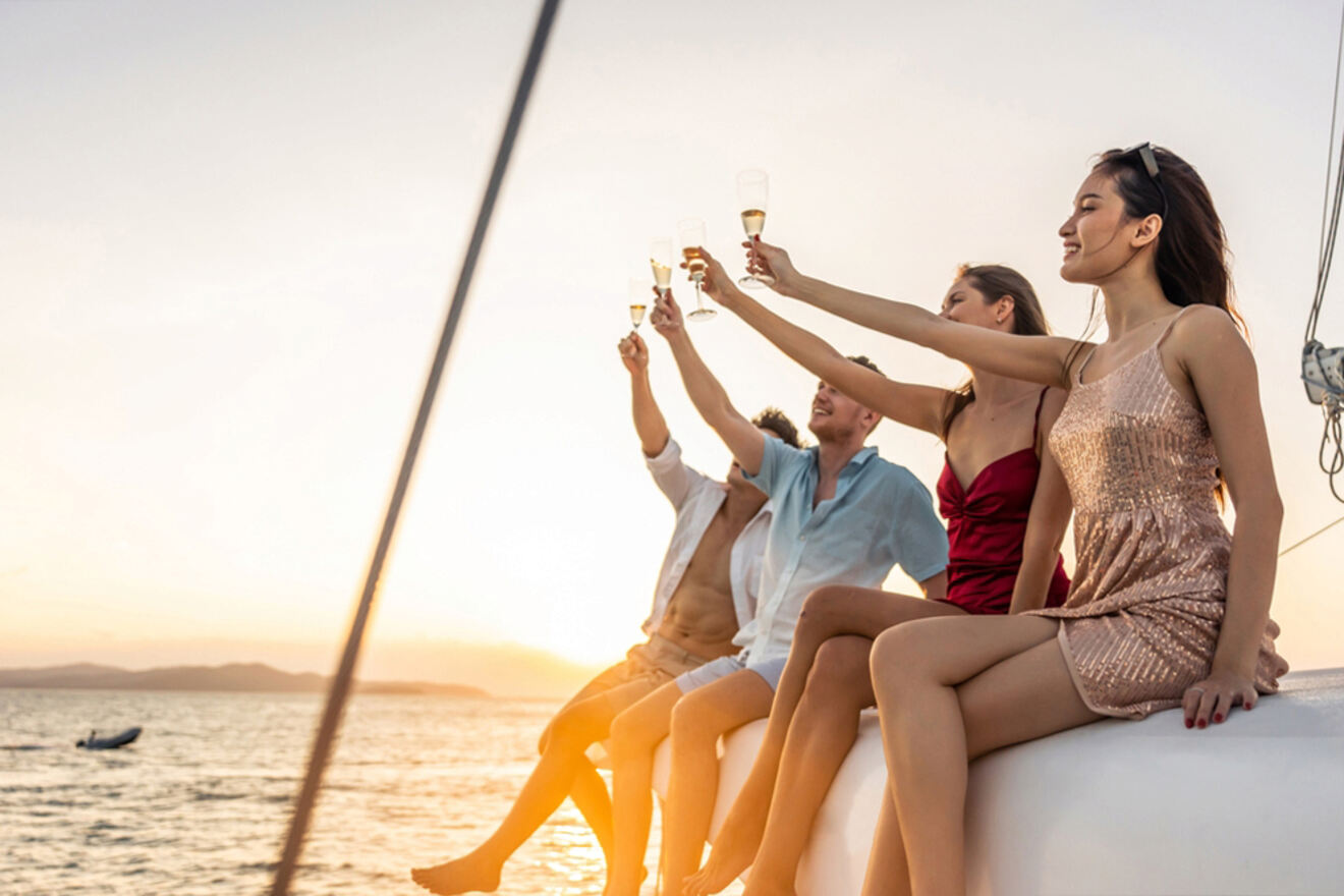 A group of friends toasting on a sailboat at sunset.