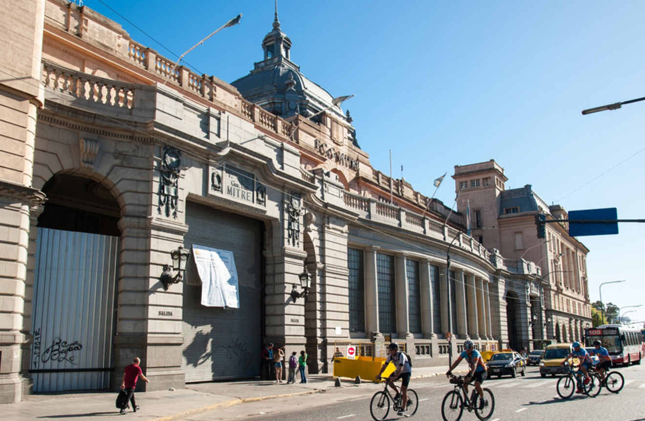 The busy exterior of Mitre Train Station in Buenos Aires, with pedestrians and cyclists in the foreground