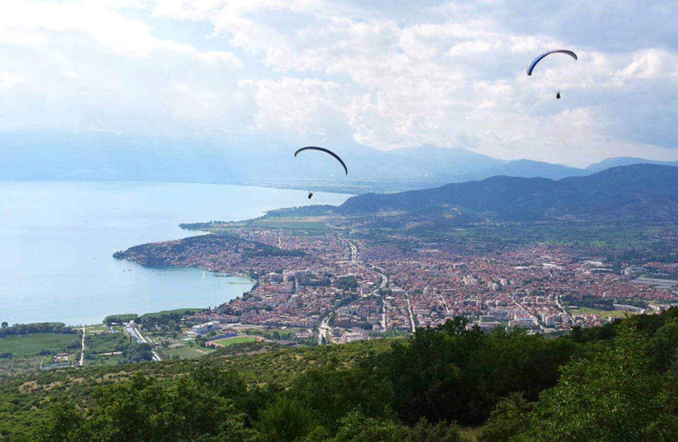 two paragliders flying over a city