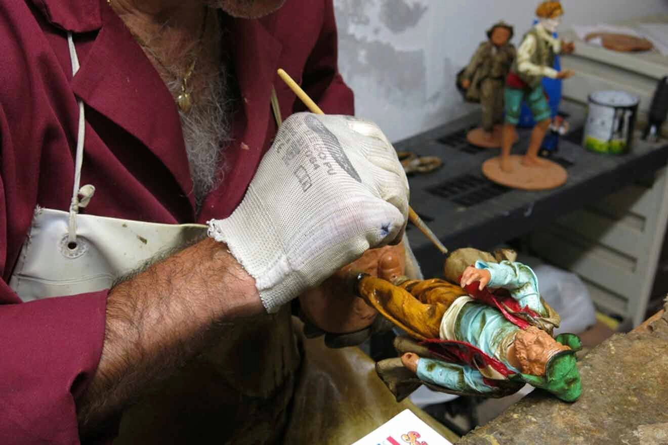 A man is working on a figurine in a workshop.