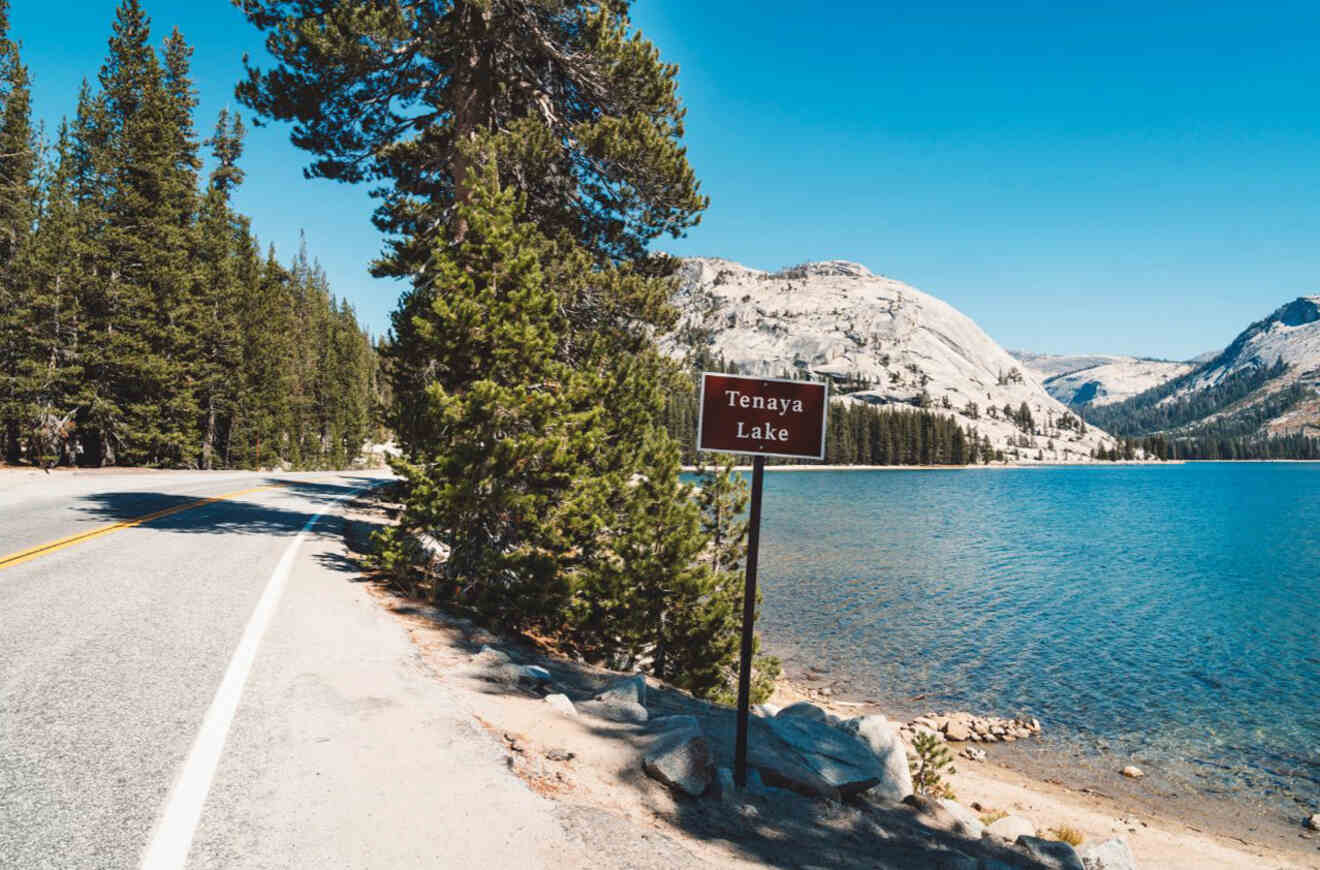 a road next to a lake with a sign Tenaya lake