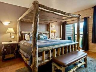 A four poster bed in a bedroom with a view of the mountains.