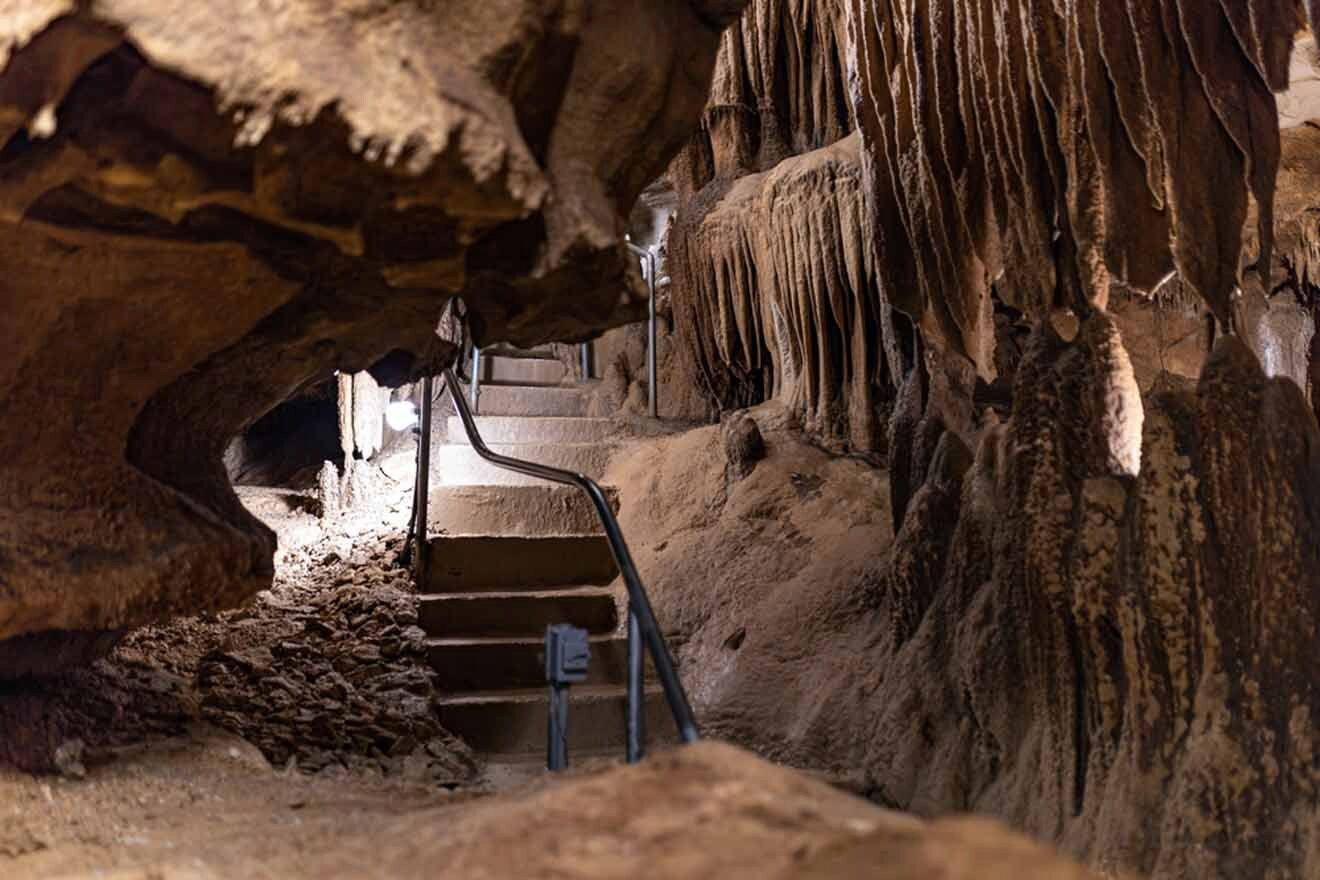 The entrance to a cave with stairs and stalactites and stalagmites.