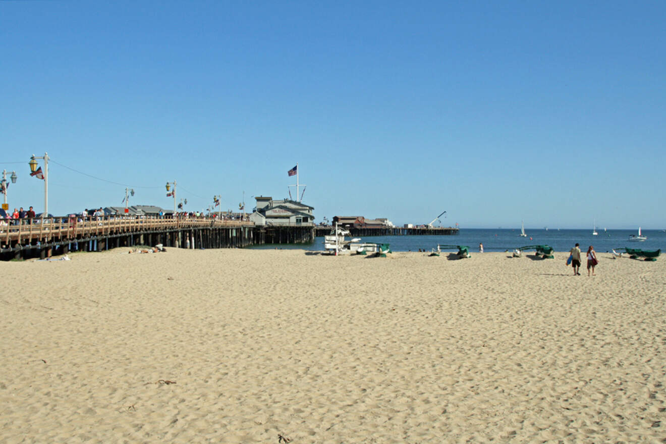 A sandy beach with a pier in the distance.