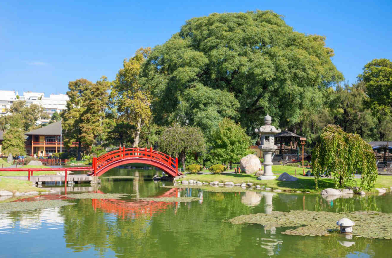a Japanese garden with a red wooden bridge crossing over a pond