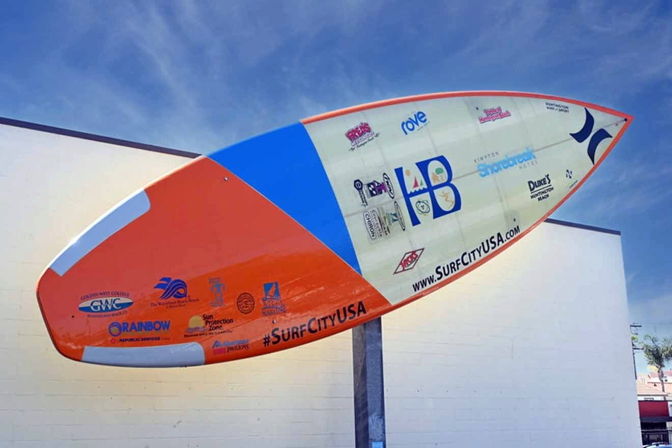 An orange and blue surfboard hanging on a wall.