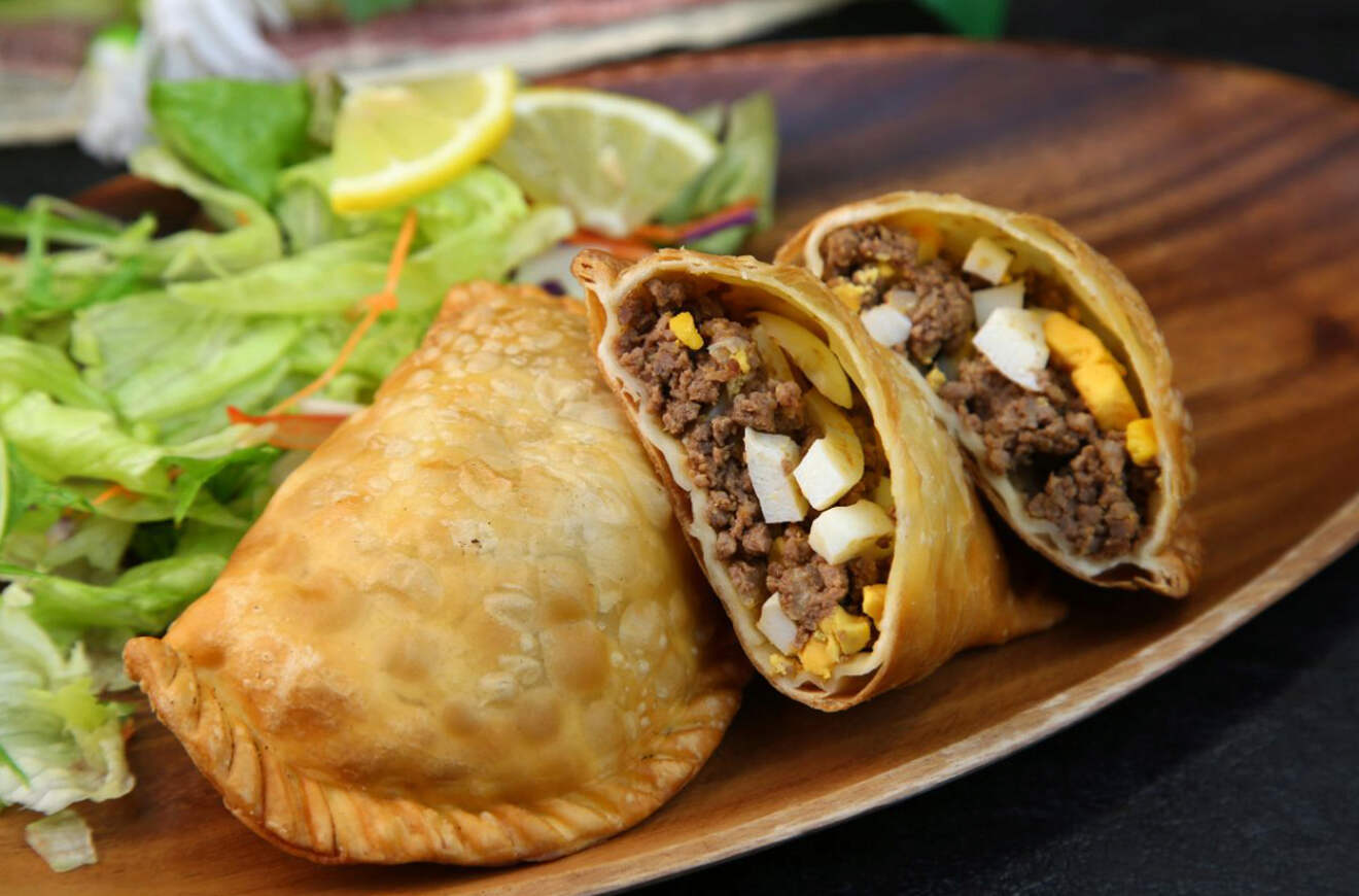 A delicious Argentine empanada cut in half, revealing a hearty filling of ground beef, hard-boiled eggs, and spices, served with a side salad