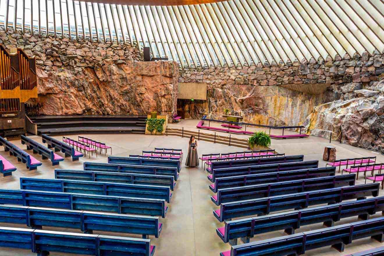 The interior of a church with benches and a rock wall.