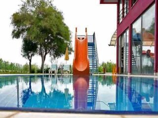 A swimming pool with a slide in front of a house.