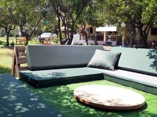 An outdoor seating area with green cushions and a table.