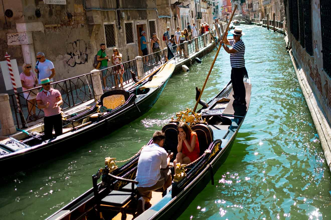 A group of people riding gondolas down a canal in Venice.
