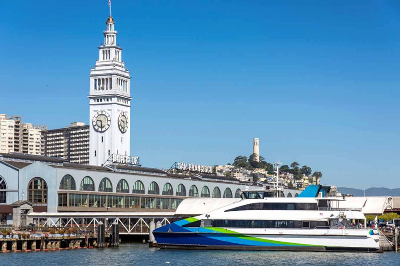A boat docked in front of a clock tower in san francisco.