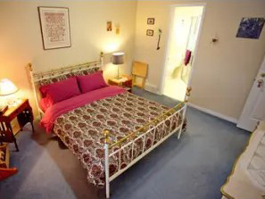 A bed or beds in a room with a pink comforter.