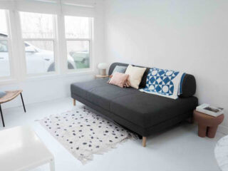 A white living room with a couch and a rug.