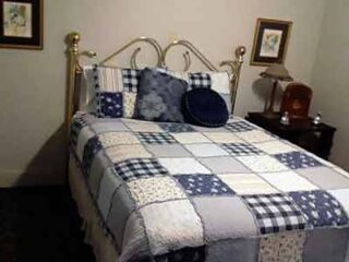 A blue and white quilted bed in a room.