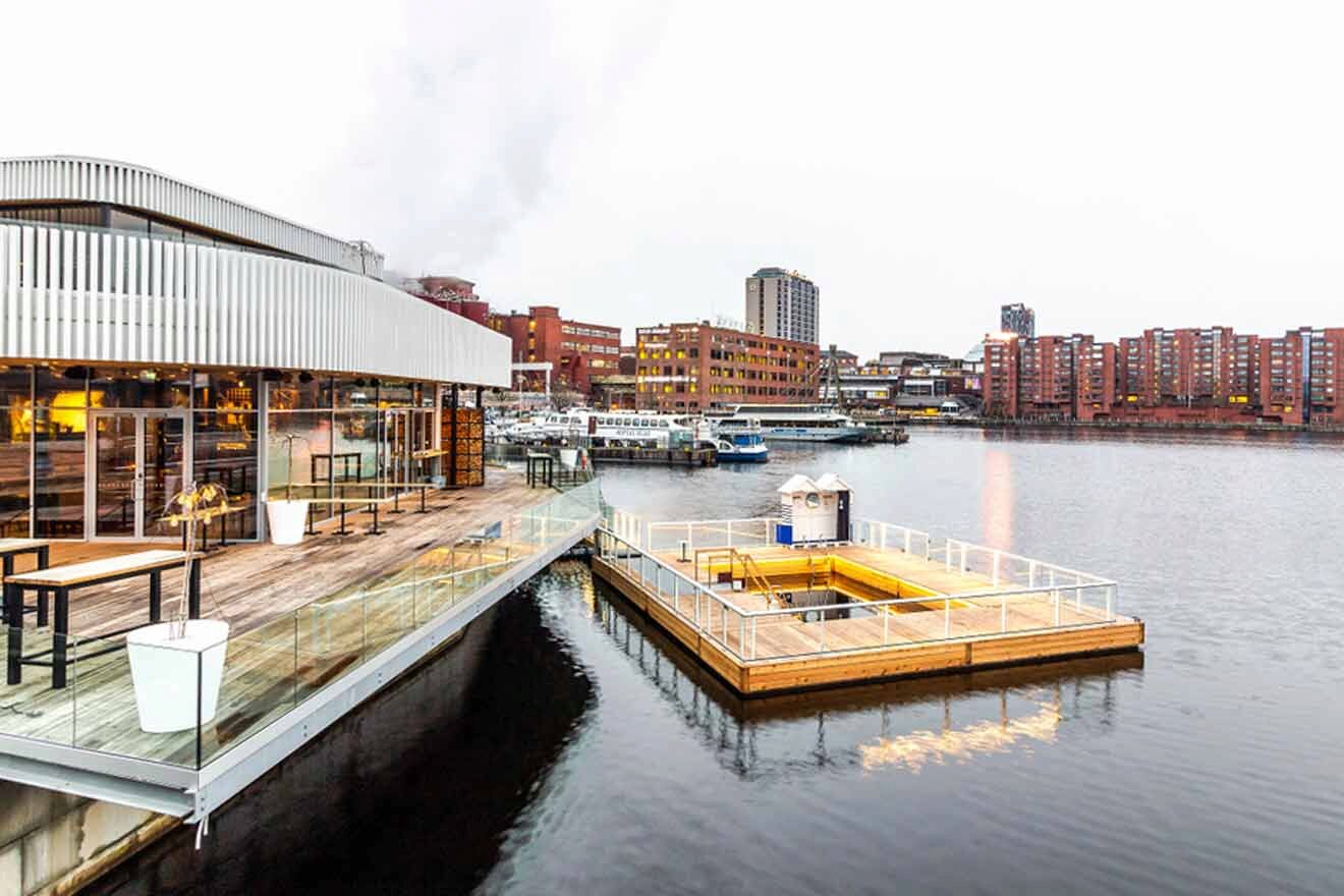 A docked sauna in the water next to a building.