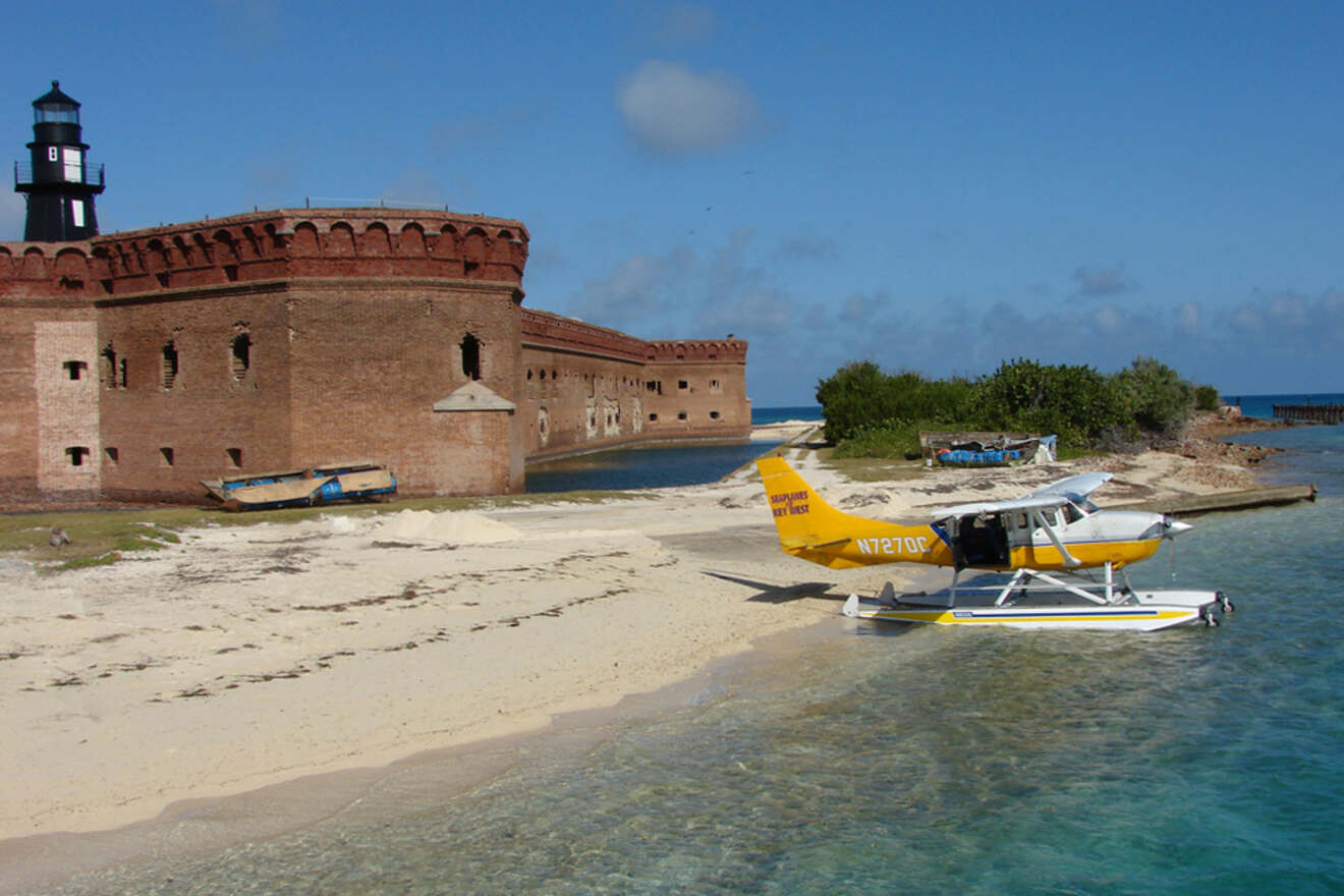 A small seaplane on the beach with a fort in the background