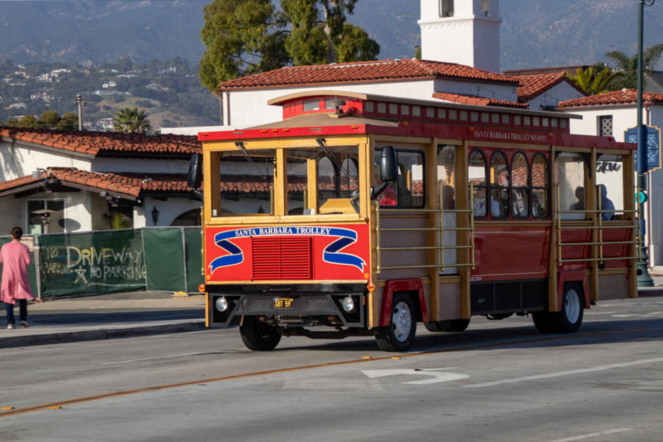 A red and yellow trolley is driving down the street.