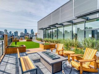 A rooftop deck with wooden furniture and a view of the city.