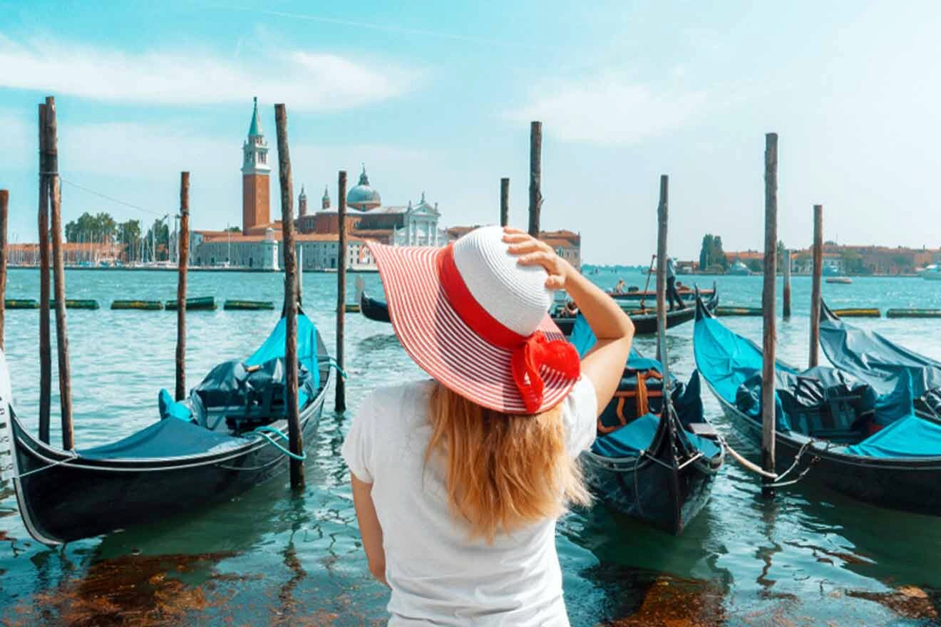 A woman in a hat looking at gondolas in venice.