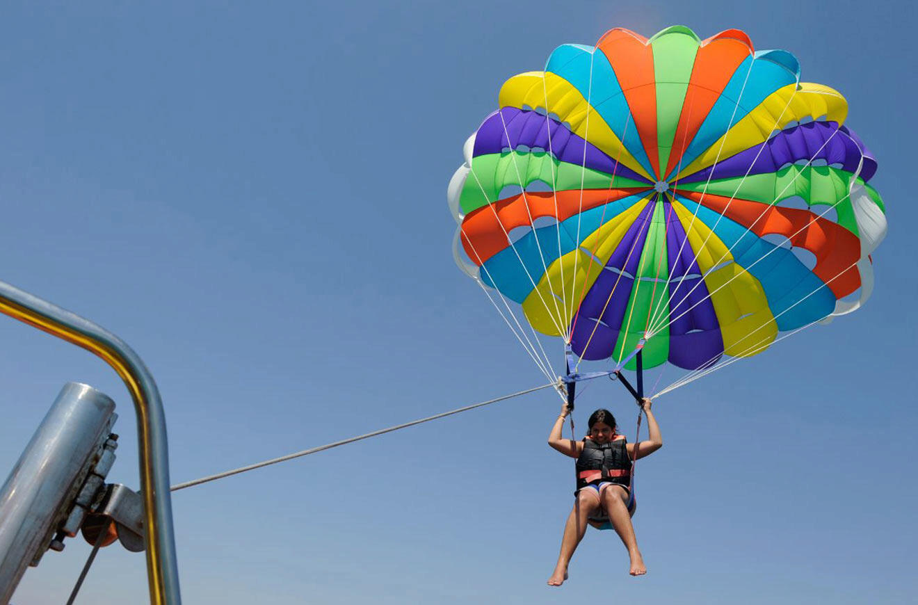 A person parasailing on a boat with a colorful parachute.