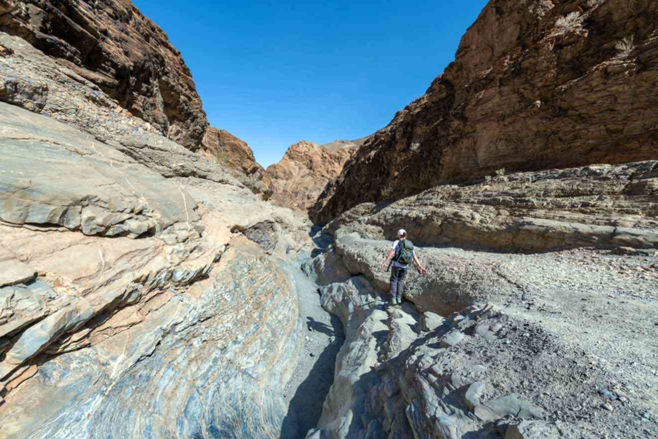 A man is walking through a narrow canyon.