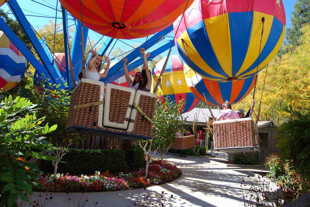 A group of people riding hot air balloons in a park.