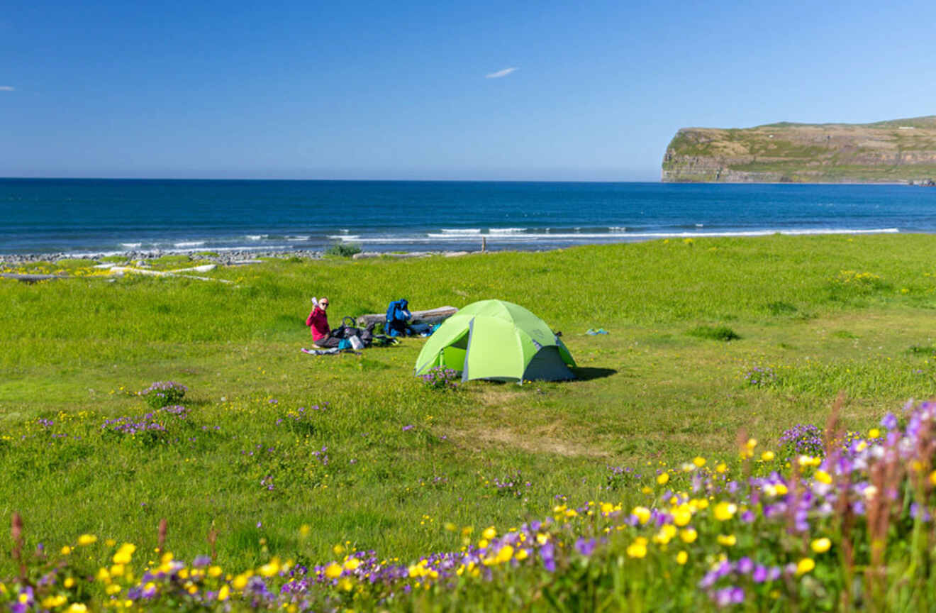 people camping with a tent on a mountain overlooking the ocean