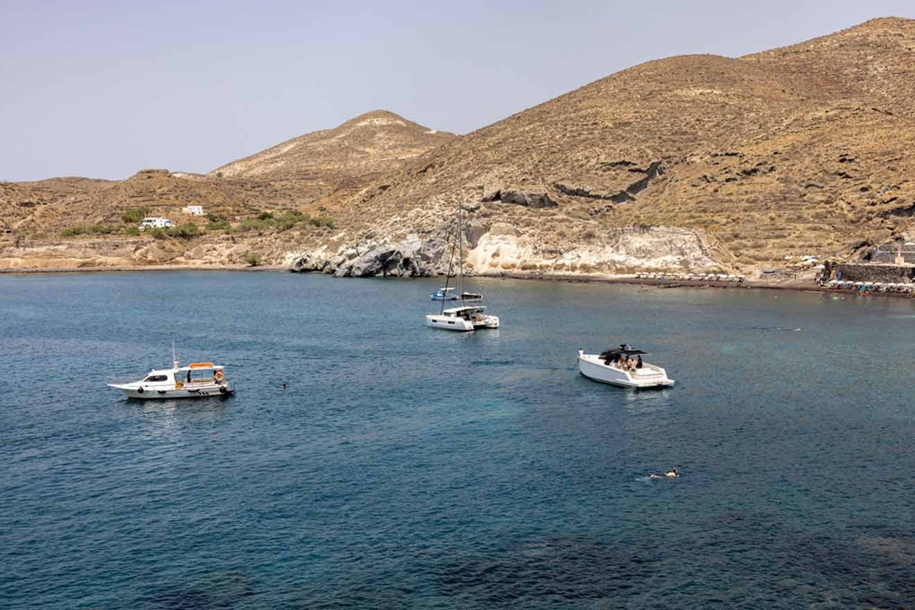 A group of boats moored in the water near a mountain.